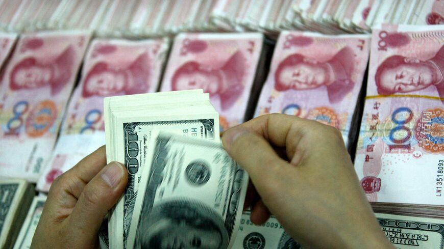 This picture taken on September 24, 2013 shows US dollar notes being counted next to stacks of Chinese 100 yuan (RMB) bank notes at a bank in Huaibei, in eastern China's Anhui province. - STR/AFP via Getty Images